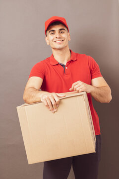 delivery man in red uniform posing with packages on a photographic background