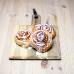 three homemade cinnamon buns on wooden plate