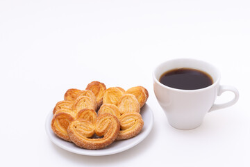White cup of hot black coffee or hot chocolate and freshly cooked heart shaped cookies on white background
