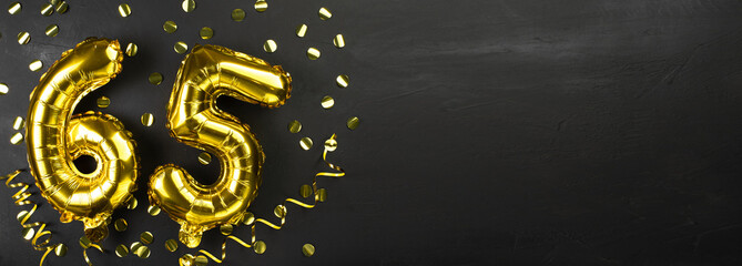 gold foil balloon number sixty-five. Birthday or anniversary card with the inscription 65. Black concrete background. Anniversary celebration. Banner.