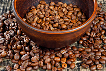 Coffee beans close up. Coffee in a clay bowl on a wooden board. Coffee texture on a black shabby table.