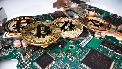 cryptocurrency mining concept with golden bitcoin coins next to a computer performant video card black background