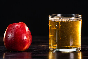 A ripe red apple and a low glass of juice on a wooden background. close-up. healthy lifestyle. healthy eating. vitamins