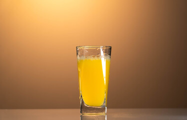 a glass of organic fresh orange juice on the reflection table with the sunset background