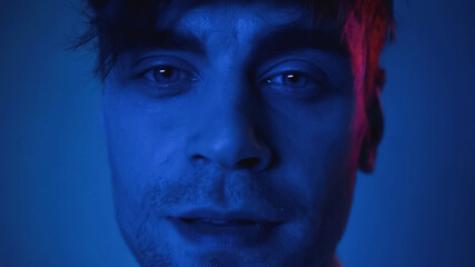 close up of man looking at camera on blue