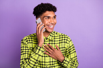 Fototapeta na wymiar Portrait of handsome cheerful brunet guy talking on phone discussing good news isolated over violet purple color background