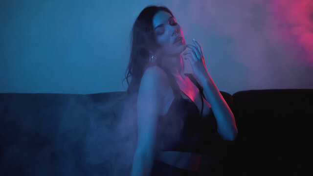 red lighting on brunette woman posing on blue with smoke