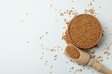 Scoop and bowl with mustard seeds on white background