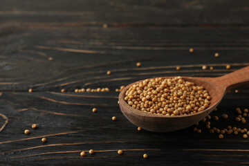 Wood spoon with mustard seeds on wooden background