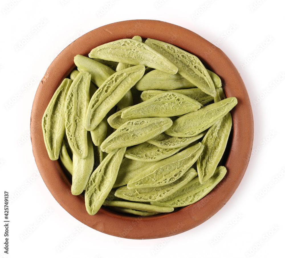 Wall mural Dried durum pasta with spinach (foglie d'ulivo) in clay bowl isolated on white background, top view, olive leaf shape