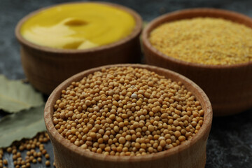 Wooden bowls with mustard seeds, sauce and powder, close up