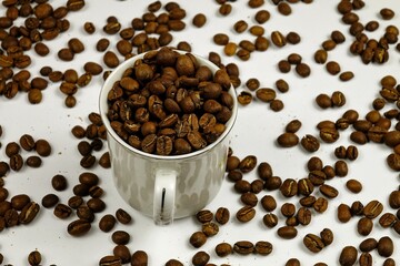 Roasted coffee beans and porcelain white coffee cup on the white table