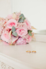 Wedding rings on background of Tender Bride's bouquet with delicate tea roses