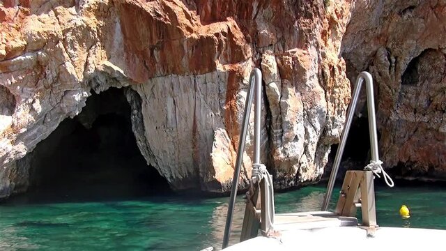 A boat leaving a submerged grotto after tourists saw it..Spectacular cave in the cliff along Marina di Camerota coast, Italy.