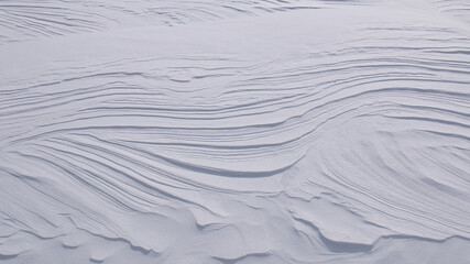 Curved lines and layers in pure white snow abstract textured background