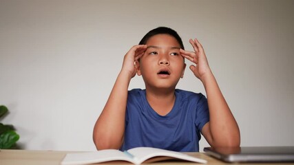 slow motion scene asian boy thinking after reading books for midterm or final test at home and using hand massage for relief symptom during lockdown time for  healthcare lifestyle concept