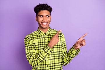 Photo of happy dark skin handsome young man point look empty space isolated on purple color background