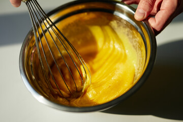 Chef mixing sugar and eggs in a metal bowl using wire whisk. Homemade cakes baking, Easter pie preparing or tasty cookie concept. High quality photo