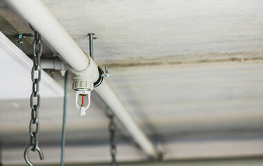 Close up image of fire sprinkler with fire in background. Fire sprinklers are part of an integrated water piping system designed for life and fire safety.