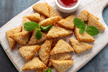 Asian Traditional Prawn Toast with Sesame seeds and sweet chilli sauce on wooden white board