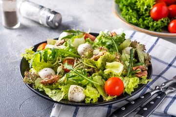 Diet and healthy salad with tomatoes, mozzarella cheese, arugula and walnuts