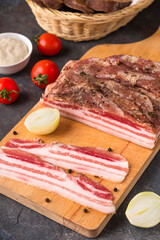 Salted bacon with spices on a wooden board. Raw pork meat with lard.