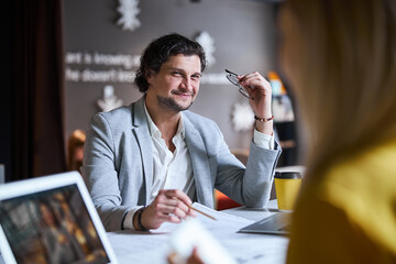 Positive delighted brunette man looking at his colleague