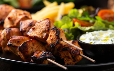 Chicken fillet souvlaki, kebabs on skewers with potato chips, salad and fresh home made tzatziki