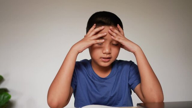 slow motion scene asian boy headache after reading books for midterm or final test at home and using hand massage for relief symptom during lockdown time for  healthcare lifestyle concept
