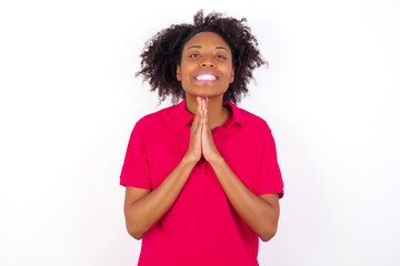 young beautiful African American woman wearing pink t-shirt against white wall keeps palms...