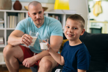 Obraz premium father and son exercise at home. drinking milk after training