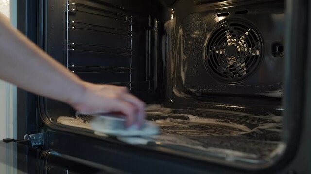Housewife doing household chores woman cleaning oven with a rag in the kitchen. High quality 4k footage