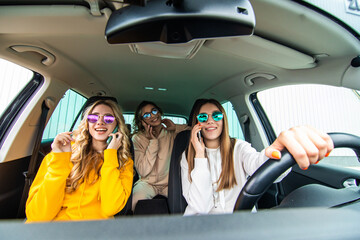 Three women friends talking in the o car speaks on phones in road trip
