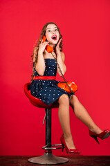 retro girl speak on phone. pretty kid talking on vintage telephone. pinup girl happy conversation. surprised kid sit on chair dial phone. communication concept. retro style. shopping online