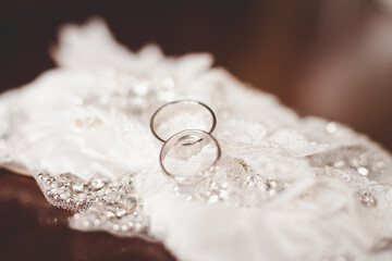 Obraz na płótnie Canvas Two wedding rings on background of wedding dress