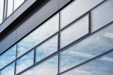 Rectangular windows, blue panes in a modern office building with a gray graphite wall 