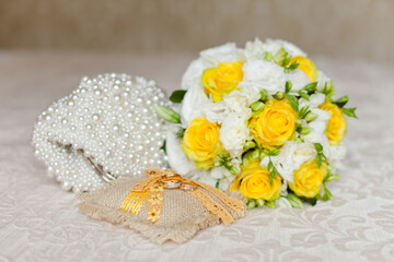 Fototapeta na wymiar Tender Bride's bouquet in yellow and white colors and wedding rings on a pillow