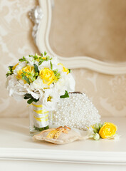 Elegant white commode with beautiful mirror and yellow wedding bouquet on it