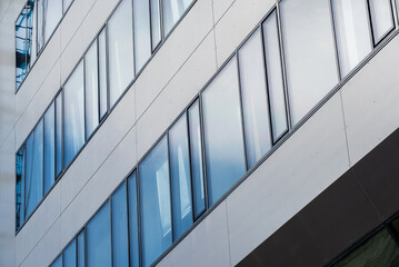 Rectangular windows, blue panes in a modern office building with a gray graphite wall 