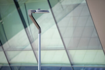 Public modern lamp against glass wall during the day