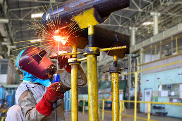 A worker welder is the process of welding a metal steel pipe system for repair with a spark in...