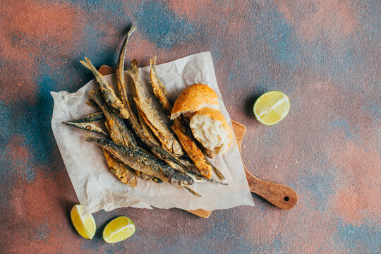 top view of fried fish, beer, baguette, lemon on concrete background