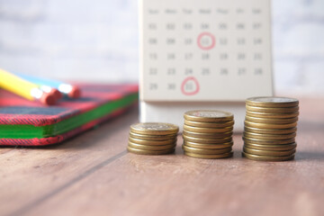 stack of coins and calendar on wooden background 