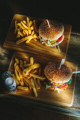 Tasty burger and french fries on wooden board
