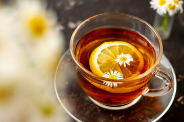 chamomile tea with lemon in a transparent cup on a black background. Breakfast concept, herbal tea.