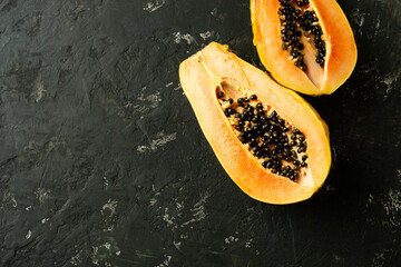 Sliced fresh and tasty papaya on a black textured background. Tropical fruit. Copy space