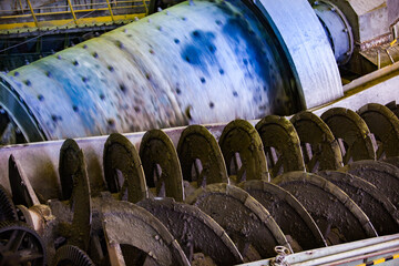 Screw conveyor close-up. Ore concentration plant. Factory ball mill on background.