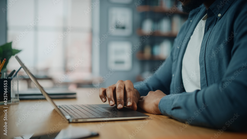 Poster close up on hands of a black african american man working on laptop computer while sitting behind de