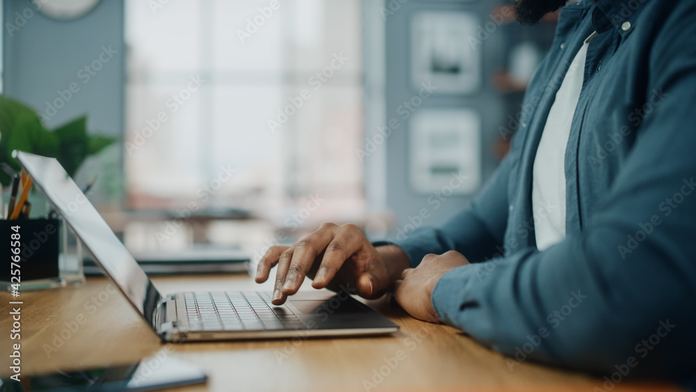 Poster close up on hands of a black african american man working on laptop computer while sitting behind de