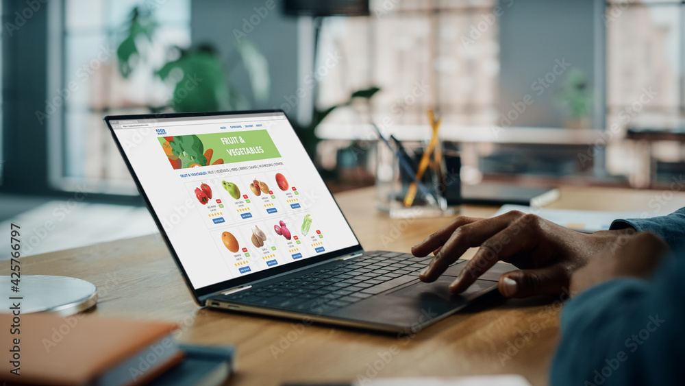 Poster close up on hands of black african american is using laptop computer with groceries delivery web pag